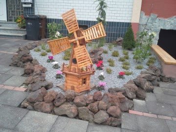 Hölzerne Windmühle in einem Steinbeet